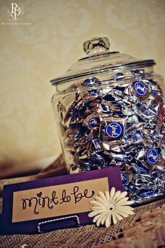 a glass jar filled with lots of silver and blue buttons sitting on top of a table