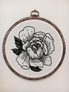 a black and white drawing of a flower in a wooden frame hanging on a wall