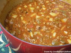 a red pot filled with meat and vegetable soup