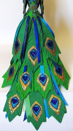 a green and blue peacock costume with feathers on it's back, sitting on a white surface