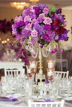 the centerpieces are filled with purple flowers and silver candlesticks for an elegant touch