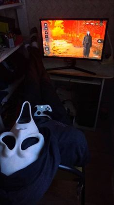 a white mask sitting in front of a tv with a video game on it's screen