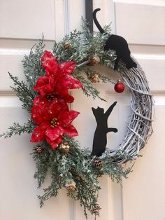 a christmas wreath decorated with poinsettis and cat silhouettes is hanging on the front door