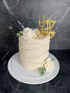 a white cake sitting on top of a plate covered in frosting and gold letters