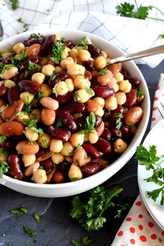 a bowl filled with beans and parsley on top of a table