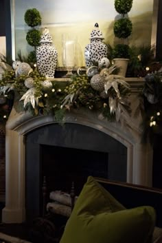 a mantel decorated with greenery and blue and white vases on top of it