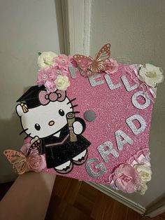 someone holding up a hello kitty sign with pink flowers and butterflies on it's side