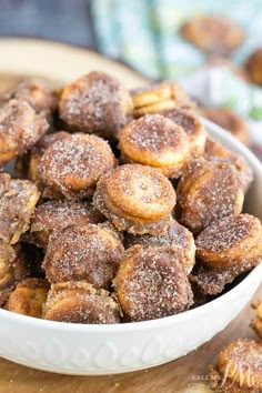 a bowl filled with sugared donuts on top of a table