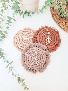 three woven coasters on a table with greenery