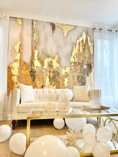 a living room filled with white balloons and gold foil paint on the wall behind it