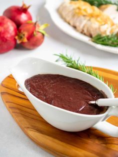 a white bowl filled with red sauce on top of a wooden platter next to other food