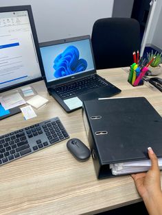 a person's hand is on an open book next to a laptop and keyboard