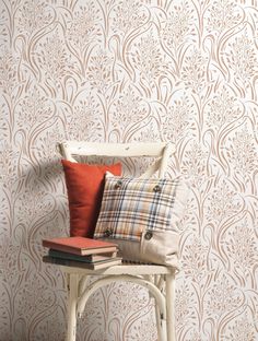 a chair with pillows on top of it in front of a wallpapered background