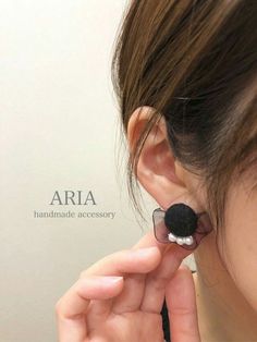 a woman is holding her ear up to the side while wearing an earring with a flower on it