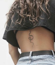 the back of a woman's stomach with a snake tattoo on her left side