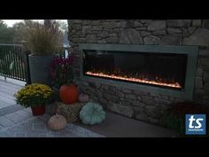 an outdoor fireplace with fake pumpkins and flowers