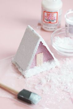 there is a small house made out of sugar and icing next to a paintbrush