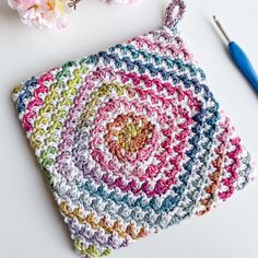 a crocheted pot holder next to a flower