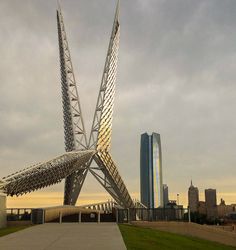 a large metal structure sitting in the middle of a park next to a tall building