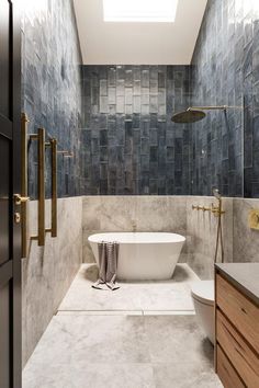 a bathroom with blue tiles and a white bathtub in the center, along with wooden cabinets