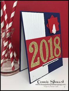 a red, white and blue card with the number 2018 on it next to two straws