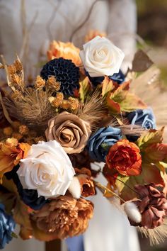 a bridal bouquet with feathers, flowers and leaves on the bride's dress