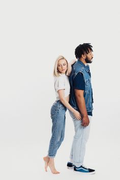 a man and woman standing next to each other in front of a white background,