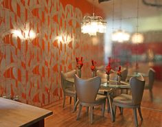 a dining room table and chairs in front of a glass wall with flowers on it