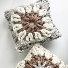 two crocheted pillows sitting next to each other on top of a white surface