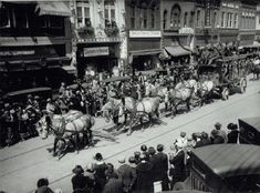 an old black and white photo of people riding on horses drawn carriages down the street