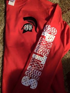 a red shirt with white and black designs on the front, along with a monogrammed t - shirt