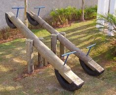 there are three wooden sees and bars in the grass near a building with palm trees