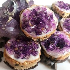 purple desserts with icing and sprinkles are on a white plate