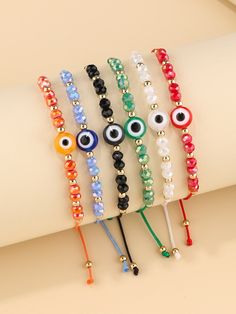 five bracelets with different colored beads and evil eyes on each one, sitting on top of