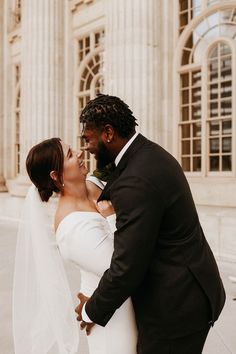 a bride and groom standing in front of a large building with columns on either side