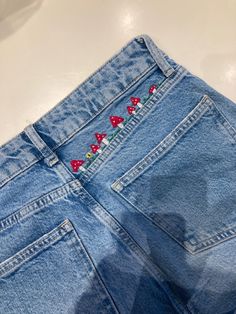 a pair of blue jean shorts with red bows on the side and embroidered flowers on the back