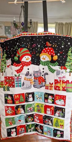 a christmas quilt hanging from the ceiling with snowmen and presents on it's sides