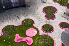 an aerial view of a park with pink and green plants on the ground, in front of a building