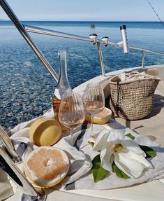 two glasses of wine are sitting on the deck of a sailboat with flowers in it