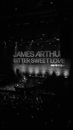 a black and white photo of a concert stage with an ad for james arthu bittersweet love