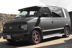 a black van parked in front of a stone wall