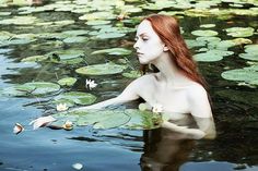 a woman floating on top of a body of water surrounded by lily pads