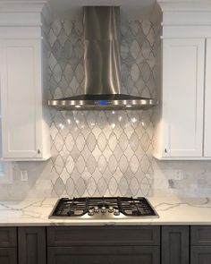 a stove top oven sitting inside of a kitchen next to white cabinets and counter tops