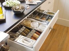 an open drawer in a kitchen filled with spices