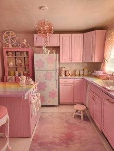 a pink kitchen with lots of cabinets and decor on the walls, including a refrigerator