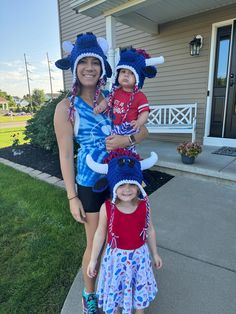 a woman and two children wearing costumes in front of a house