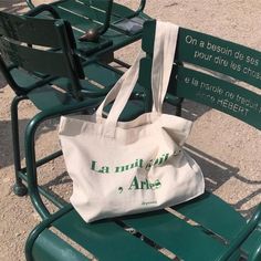 a white bag sitting on top of a green park bench next to two green benches