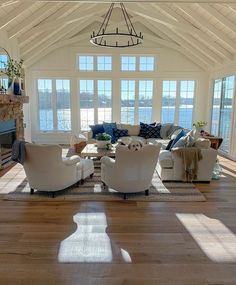 a living room filled with furniture and a fire place in front of a window overlooking the water