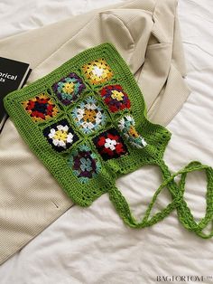 a green crocheted bag sitting on top of a bed next to a book