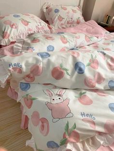 a bed covered in pink and blue apples with an animal on it's head